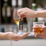 Drunk man giving car key to woman, on blurred background. Don't drink and drive concept