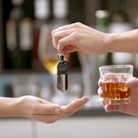 Drunk man giving car key to woman, on blurred background. Don't drink and drive concept