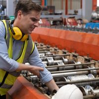 Men Caucasian engineer getting his hand stuck in industrial machine with serious injured inside factory or heavy machine production line. Accident with factory worker, non safety work environment.